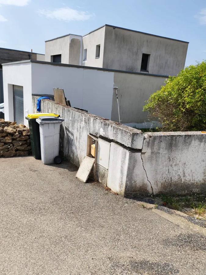 Façade partiellement remise en peinture, rouleau sur perche contre le mur — chantier coordonné